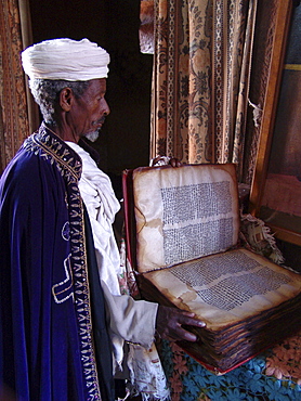 Religion, ethiopia. Priest at church of saints gabriel and rafael, lalibela, with an ancient parchment book