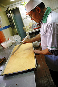 Colombia baker cutting a cake at a bakery in ciudad bolivar, bogota