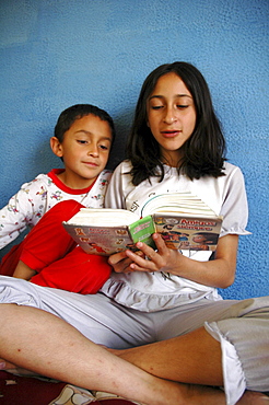 Colombia day in the life series: hugo andres, 7, of ciudad bolivar, bogota, being read to by his sister lineth