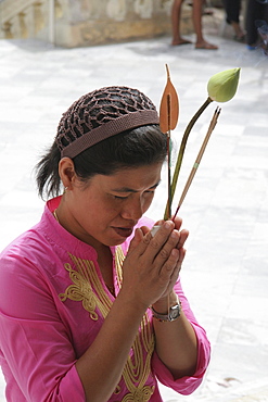 Thailand woman praying while she holds a lotus flower, ancient buddhist temple and stupa of phra pathom chedi, nakhon pathom