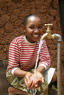 Tanzanian girl taking pleasure at the abundant supply of fresh, safe drinking water which now runs to her house thanks to a development project of caritas tanzania, funded by caritas australia. Mvango village, same, in the north-east near kilimanjaro