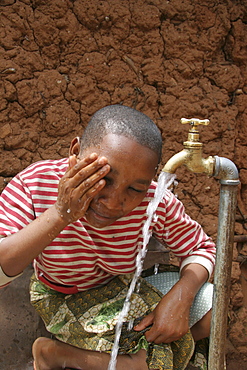 Tanzanian girl taking pleasure at the abundant supply of fresh, safe drinking water which now runs to her house thanks to a development project of caritas tanzania, funded by caritas australia. Mvango village, same, in the north-east near kilimanjaro