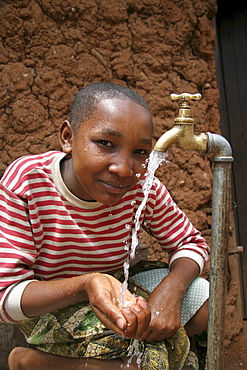 Tanzanian girl taking pleasure at the abundant supply of fresh, safe drinking water which now runs to her house thanks to a development project of caritas tanzania, funded by caritas australia. Mvango village, same, in the north-east near kilimanjaro