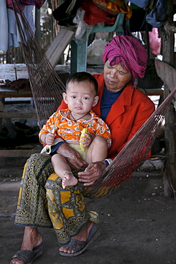 CAMBODIA Grandmother and baby in hammock. Don Tok village, Kampot, lies beside a river estuary and is often flooded by sea water, a consequence of climate change during the last few years. CRS is studying the problem through its partner agency, SCW (Save Cambodian Wildlife). These people have to endure the inconvenience of daily flooding around their homes. photo by Sean Sprague