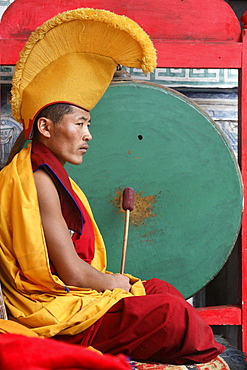 Monk beating traditional drum called gong, int he courtyard of chiwang monastery during mani rimdu festival. chiwang monastery, solu khumbu, nepal