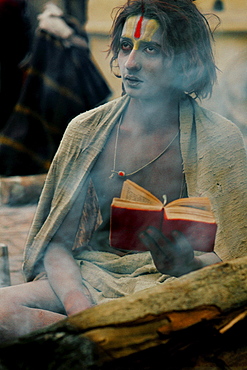 A young sadhu reads holy scripture near fire. Worship is part of daily life. Some sadhus chant mantras. gayatri mantra is of several mantras that sacred incantations or mystical formulas of ancient literature. gayatri mantra given by brahma mentioned in rigveda is named after consort of brahma: o that glory- of savitri most high. Oh divine us mediate upon. it inspire understanding. goal of recitation is to attain realization. Practice lead mind into a transcendental union with deity.Pashupatinath, kathmandu, nepa