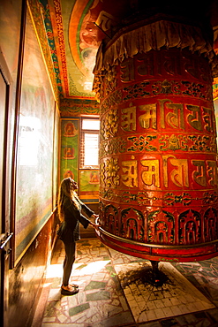 Woman praying at a Buddhist prayer wheel in Bouddha (Boudhanath) temple, UNESCO World Heritage Site, Kathmandu, Nepal, Asia