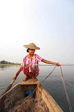 A young woman pulls in her nets at the end of the day on Indawgyi Lake, Kachin State, Myanmar (Burma), Asia