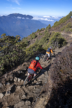 Mountain bikes speed past in a blur along a Enduro style single track trail in the Nepal Himalayas near the Langtang region, Nepal, Asia