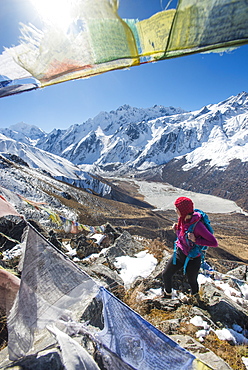 A woman trekking in the Langtang valley in Nepal stands on the top of Kyanjin Ri and looks out towards Ganchempo in the distance, Langtang Region, Nepal, Asia