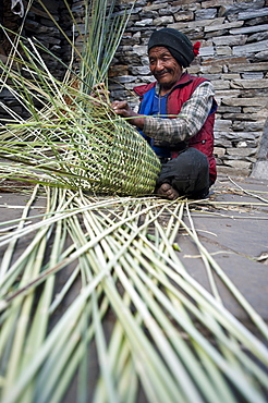 A man uses great skill and traditional knowledge to make a bamboo basket (Doko) by hand, Manaslu Region, Nepal, Asia