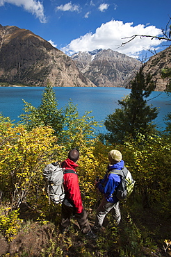 Trekkers look out at the turquoise blue Phoksundo lake, Dolpa Region, Nepal, Asia