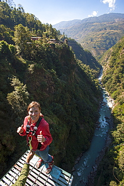 Standing on then edge, a girl prepares herself to take a bungy jump backwards, Nepal, Asia