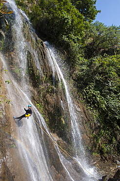 A girl pauses to smile for the camera while canyoning in a waterfall, Nepal, Asia