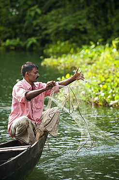 A man pulls in his fishing net on Kaptai Lake, Chittagong Hill Tracts, Bangladesh, Asia