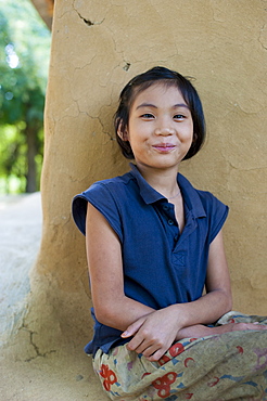 A girl from Rangamati sits outside her mud walled house near Kaptai lake, Chittagong Hill Tracts, Bangladesh, Asia