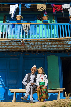 A old Nepali couple wearing traditional dress sit outside their house in Diktel, Khotang District, Nepal, Asia