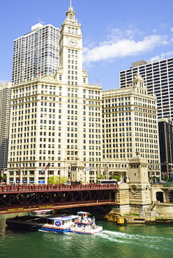 Sightseeing boat passing under DuSable Bridge on the Chicago River with Wrigley Building behind, Chicago, Illinois, United States of America, North America