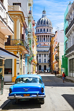 A classic car parked on the street next to colonial buildings with the former Parliament Building in the background, Havana, Cuba, West Indies, Caribbean, Central America