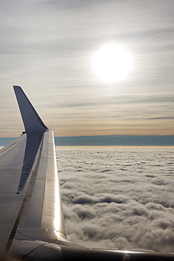 Plane wing with low lying clouds and sunburst, United Kingdom, Europe