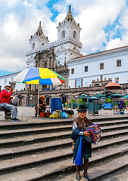 A traditionally dressed indigenous woman sells textiles in central Quito, Ecuador, South America