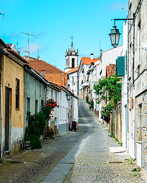 Narrow cobblestone street looking towards Santiago Church in Belmonte, Castelo Branco, Portugal, Europe