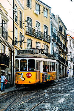 Traditional yellow electric tram in a narrow street in Alfama, Lisbon, Portugal, Europe