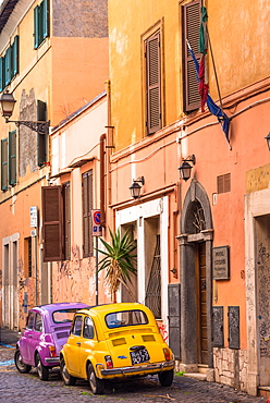 Two vintage Fiat 500s with Roma number plates parked in colourful backstreet of Trastevere, Lazio, Italy, Europe