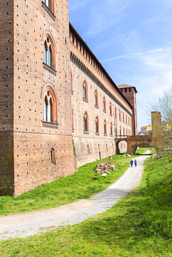 Two people walk in the park of Castello Visconteo (Visconti Castle), Pavia, Pavia province, Lombardy, Italy, Europe