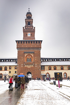 Tourist walks in the courtyard of Sforza Castle during a snowfall, Milan, Lombardy, Northern Italy, Italy, Europe