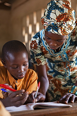 A teacher helping a young student at a school, Ghana, West Africa, Africa