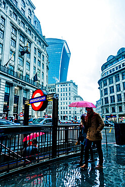 Underground sign and people entering entering tube station on a rainy day, London, England, United Kingdom, Europe