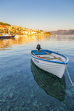 Small boat anchoring outside the old town at first sunlight, Korcula Town, Croatia, Europe