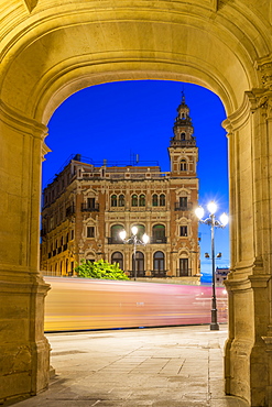 Light trails of the tram passing historical building at Plaza Nueva at dusk, Seville, Andalusia, Spain, Europe