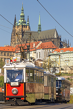 Tourist tram passing a bridge over Vltava River with view to Prague Castle in the background, Prague, Bohemia, Czech Republic, Europe