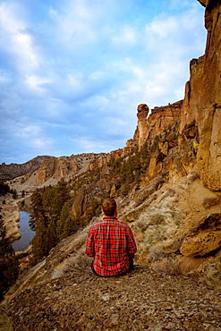 Man wearing a flannel shirt looking at a large rock formation, Oregon, United States of America, North America