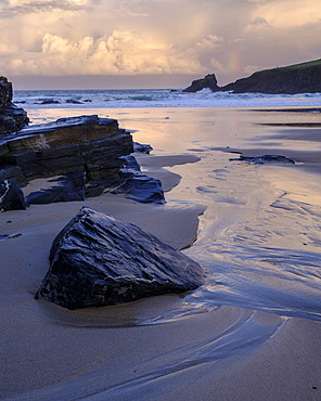 Atlantic clouds reflect dawn light onto the wet sands and rocks of Trevone, near Padstow in Cornwall, England, United Kingdom, Europe