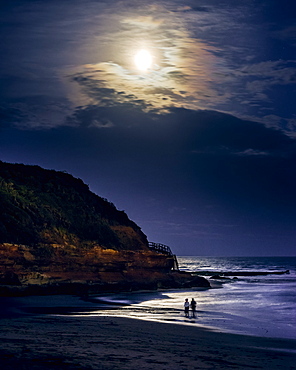 Two ladies paddle whilst watching the full Blood Moon, shortly after an eclipse at Orcombe Point, Exmouth, Devon, England, United Kingdom, Europe