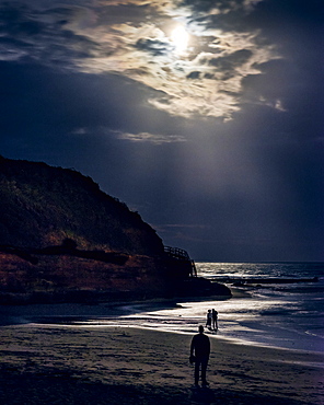 Someone observes two ladies whilst watching the full Blood Moon, shortly after an eclipse at Orcombe Point, Exmouth, Devon, England, United Kingdom, Europe