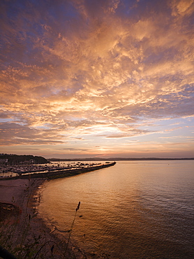 Colourful sunset view of Breakwater Beach and the harbour wall of Brixham, Devon, England, United Kingdom, Europe