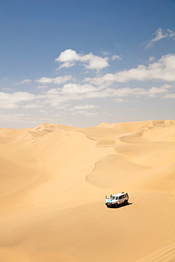 A car pictured within the Sandwich Harbour dunes, Skeleton Coast at midday, Namibia, Africa