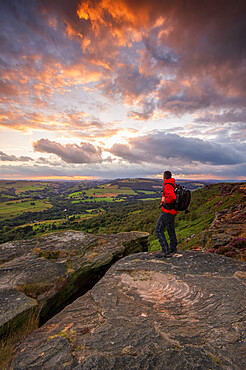 A walker standing on Curbar Edge at sunset, Derbyshire, Peak District, Derbyshire, England, United Kingdom, Europe