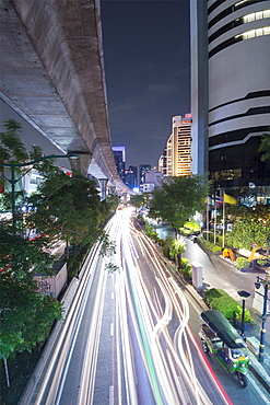 View of elevated skytrain track and traffic light trails on Sukhumvit Road in downtown Bangkok, Thailand, Southeast Asia, Asia