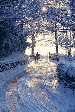 Man and child walking down a snow covered road in winter near Arthington, West Yorkshire, England, United Kingdom, Europe