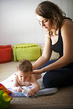 Baby massage lesson with a certified masseur, a young mother learns how to massage her 1-year old son.