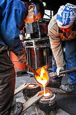 Takahiro Koizumi and his assistant Kohei ishimori are pouring molten iron into the mold, to make a iron teapot or tetsubin, nanbu tekki,Workshop of Koizumi family,craftsmen since 1659, Morioka, Iwate Prefecture, Japan