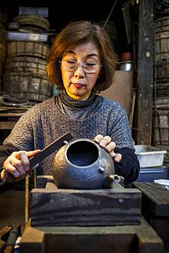 Morihisa Suzuki  is putting the finishing touches at iron teapot or tetsubin, the only woman who has made teapots in the nearly 400 years of history that has molten iron crafts in Iwate, in Workshop of Morihisha Suzuki,craftsmen since 1625, nanbu tekki, Morioka, Iwate Prefecture, Japan