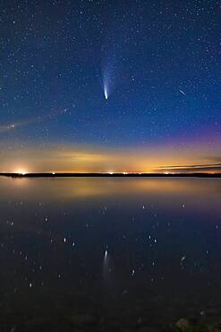 Comet NEOWISE (C/2020 F3) reflected in the still waters this night of Crawling Lake in southern Alberta. A dim aurora at right colours the sky magenta. Lingering twilight colours the sky blue. A meteor or more likely a flaring satellite appears at right and is also reflected in the water. Even in this short exposure, the two tails ' dust and ion ' are visible. This was July 20, 2020.