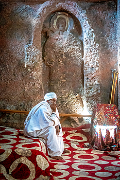 A man sits in front of a worn sculpture inside Bet Golgotha (House of Golgotha Mikael), known for its arts and said to contain the tomb of King Lalibela) in Lalibela, Ethiopia