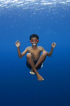 Local children swimming from small outrigger canoes using home made goggles, Alor Island, Nusa Tenggara, Indonesia, Pacific Ocean